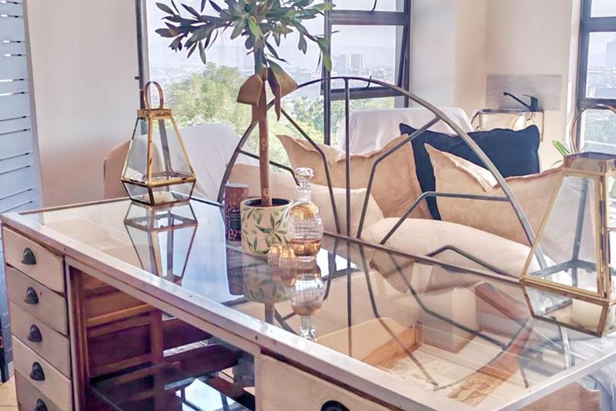 A bright living area featuring exposed timber ceiling beams, large windows with city views, and tiled flooring.
