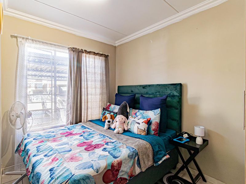 A cozy bedroom featuring neutral wall tones, decorative ceiling cornicing, and a built-in wardrobe for storage.