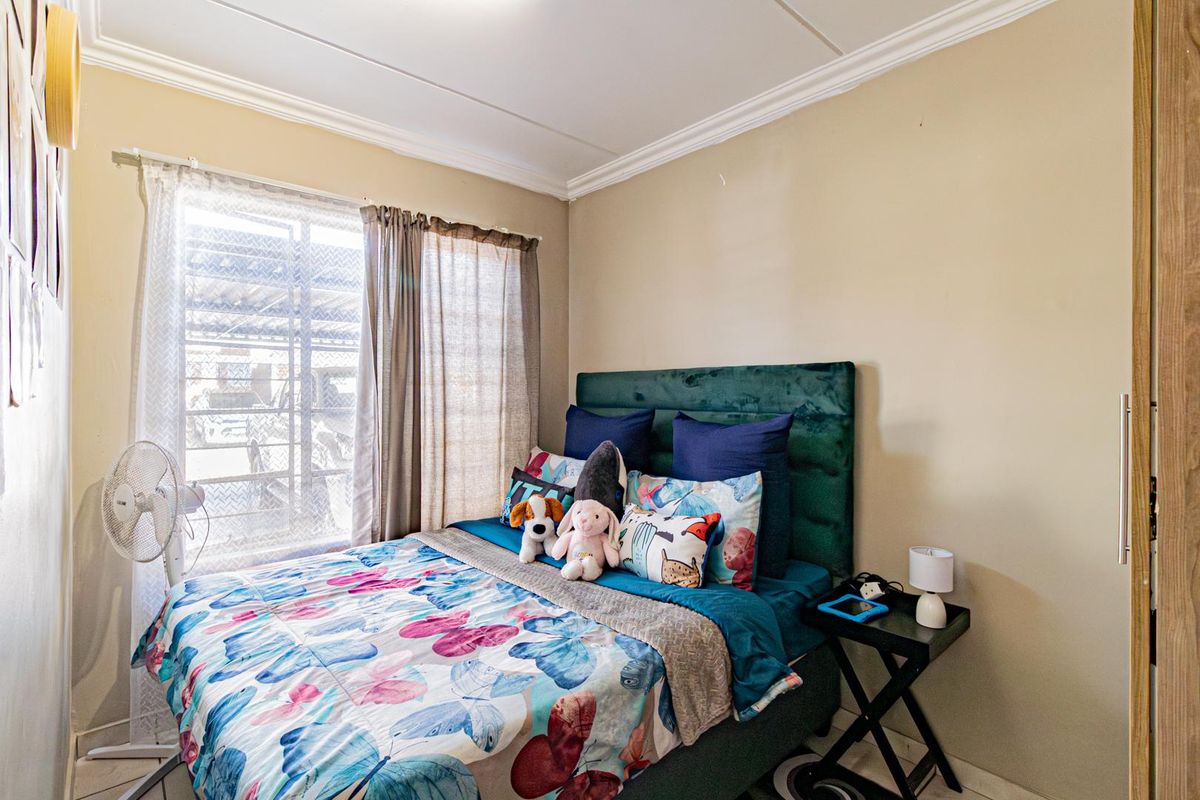 A cozy bedroom featuring neutral wall tones, decorative ceiling cornicing, and a built-in wardrobe for storage.