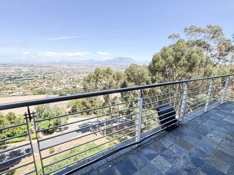 An elevated balcony featuring durable slate tile flooring and a modern stainless steel balustrade, offering expansive panoramic views of the surrounding landscape.
