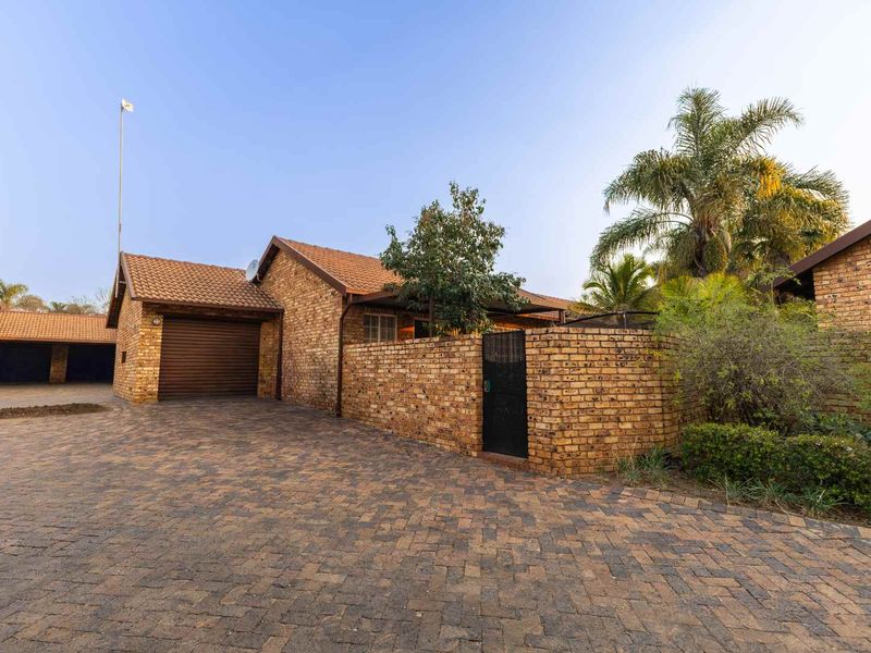 Front exterior view of a face brick townhouse featuring a paved driveway, private walled entrance, and an integrated single garage.