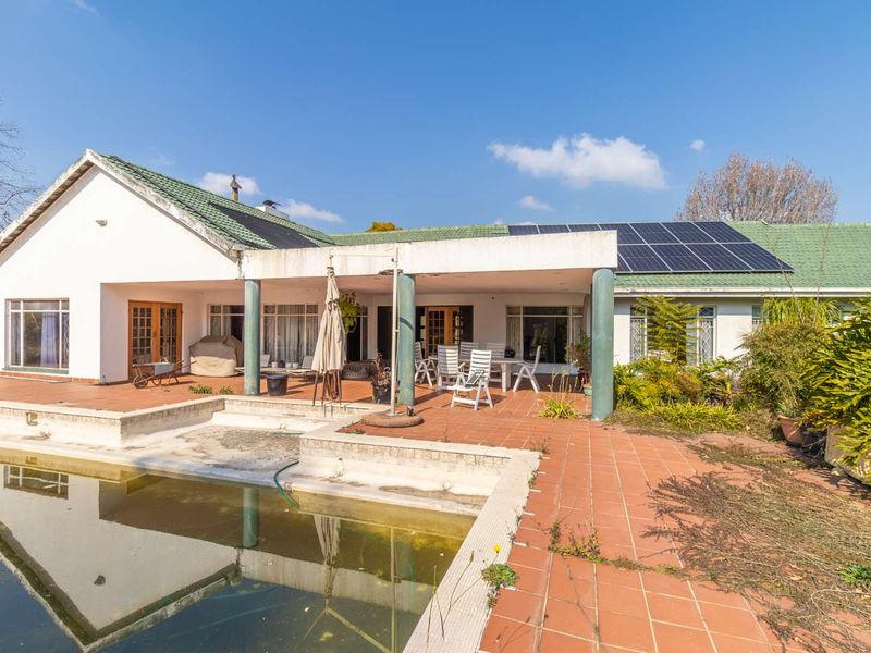 Rear view of the property featuring a covered patio, tiled terrace, and a swimming pool with solar panels installed on the roof.