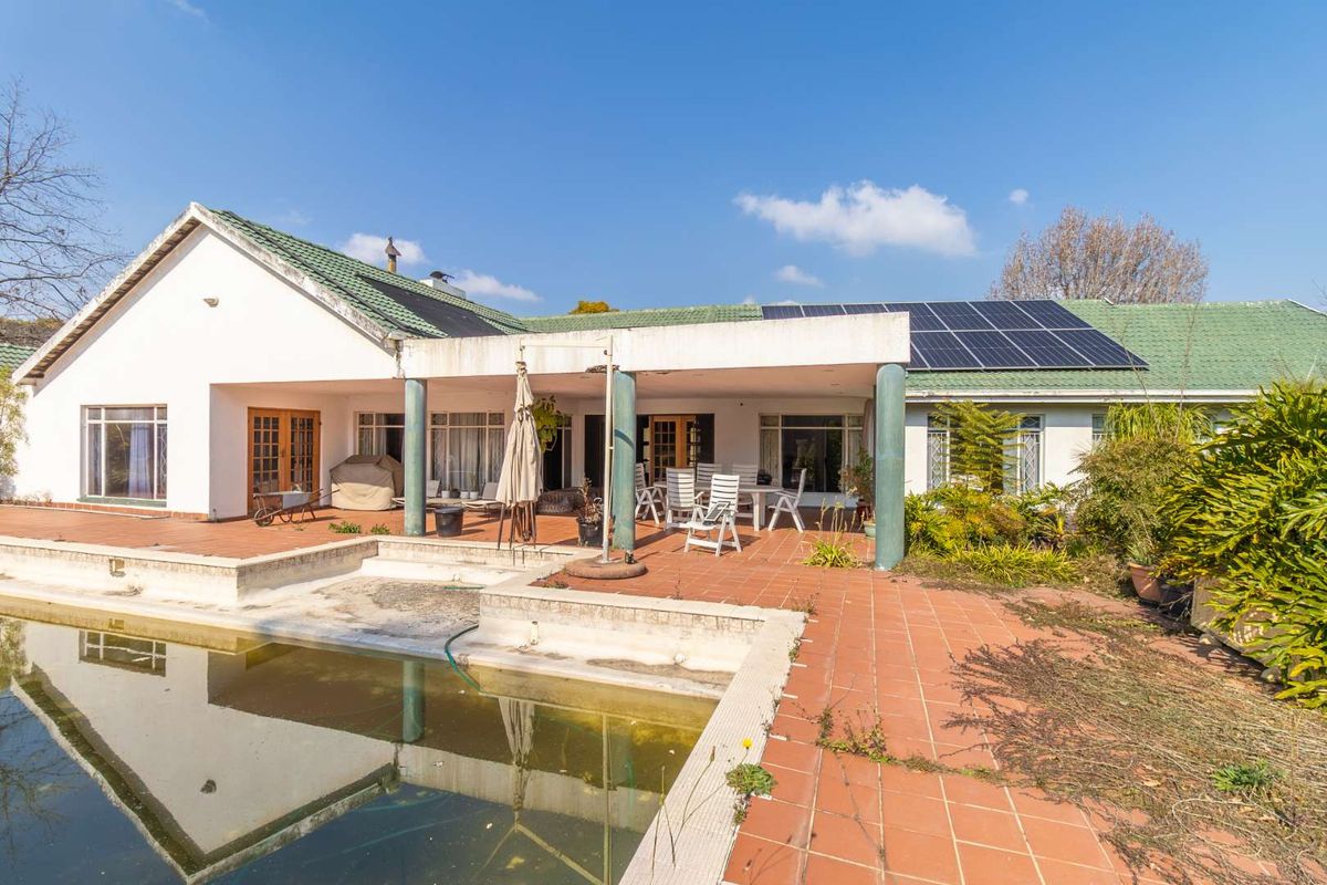 Rear view of the property featuring a covered patio, tiled terrace, and a swimming pool with solar panels installed on the roof.