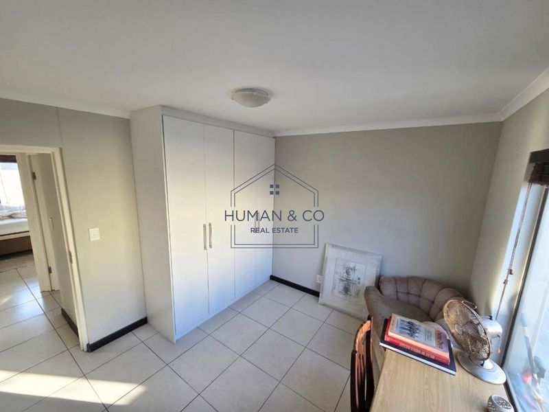 A bedroom featuring neutral wall tones, tiled flooring, and a built-in wardrobe, offering a clean and functional living space.