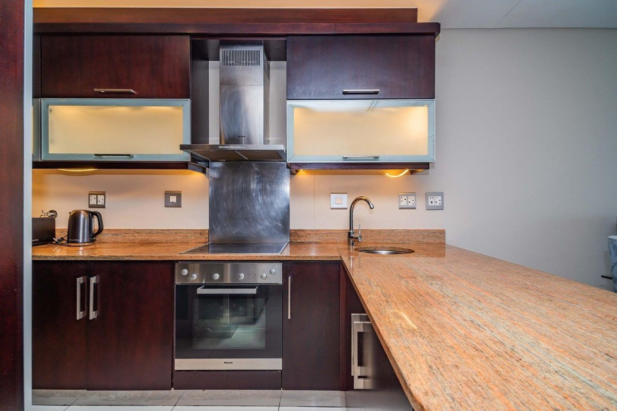 Modern kitchen featuring dark wood cabinetry, granite countertops, stainless steel appliances, and integrated lighting, providing a functional and stylish cooking space.