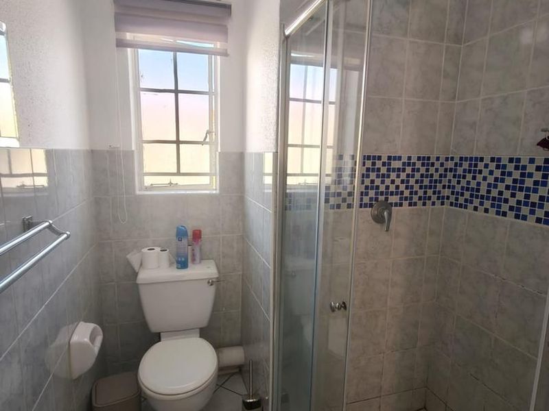 A functional bathroom featuring a glass-enclosed shower, toilet, and tiled finishes throughout, providing a practical layout for daily use.