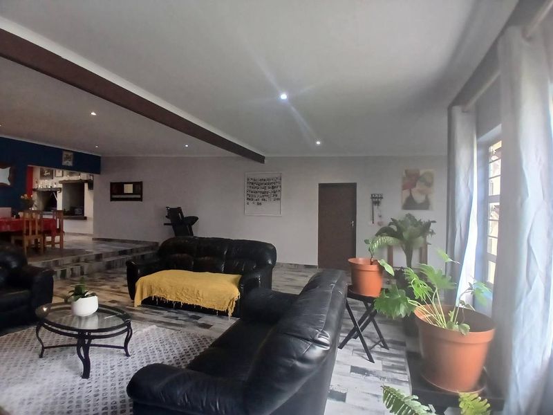 Spacious open-plan living area featuring tiled flooring, recessed lighting, and a raised dining platform, offering a versatile layout for family living.