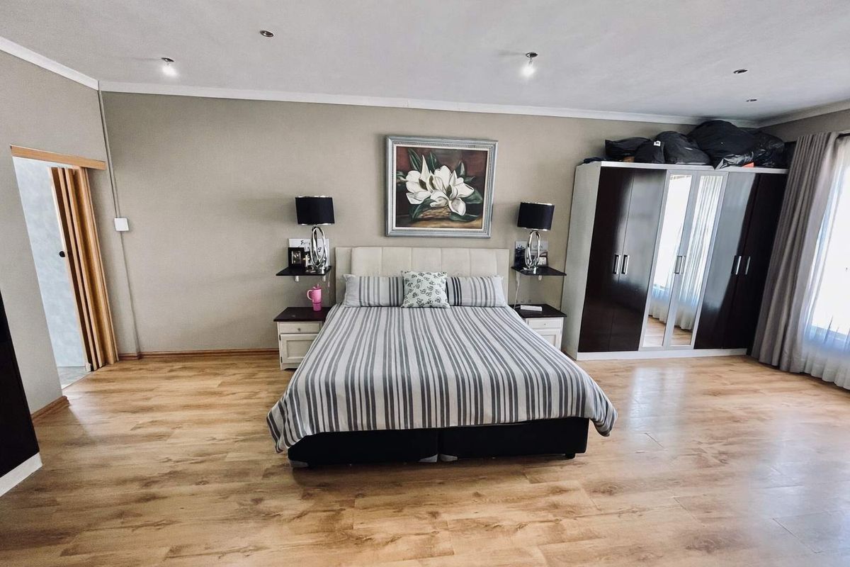 Spacious bedroom featuring light wood-look flooring, recessed ceiling lighting, and built-in wardrobe cabinetry.