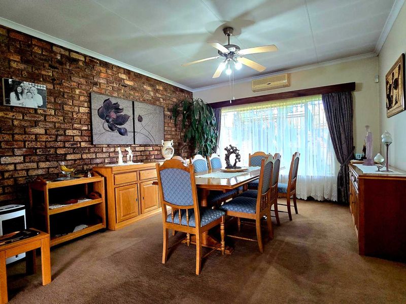 Dining room featuring an exposed brick accent wall, ceiling fan, and split-system air conditioning unit.