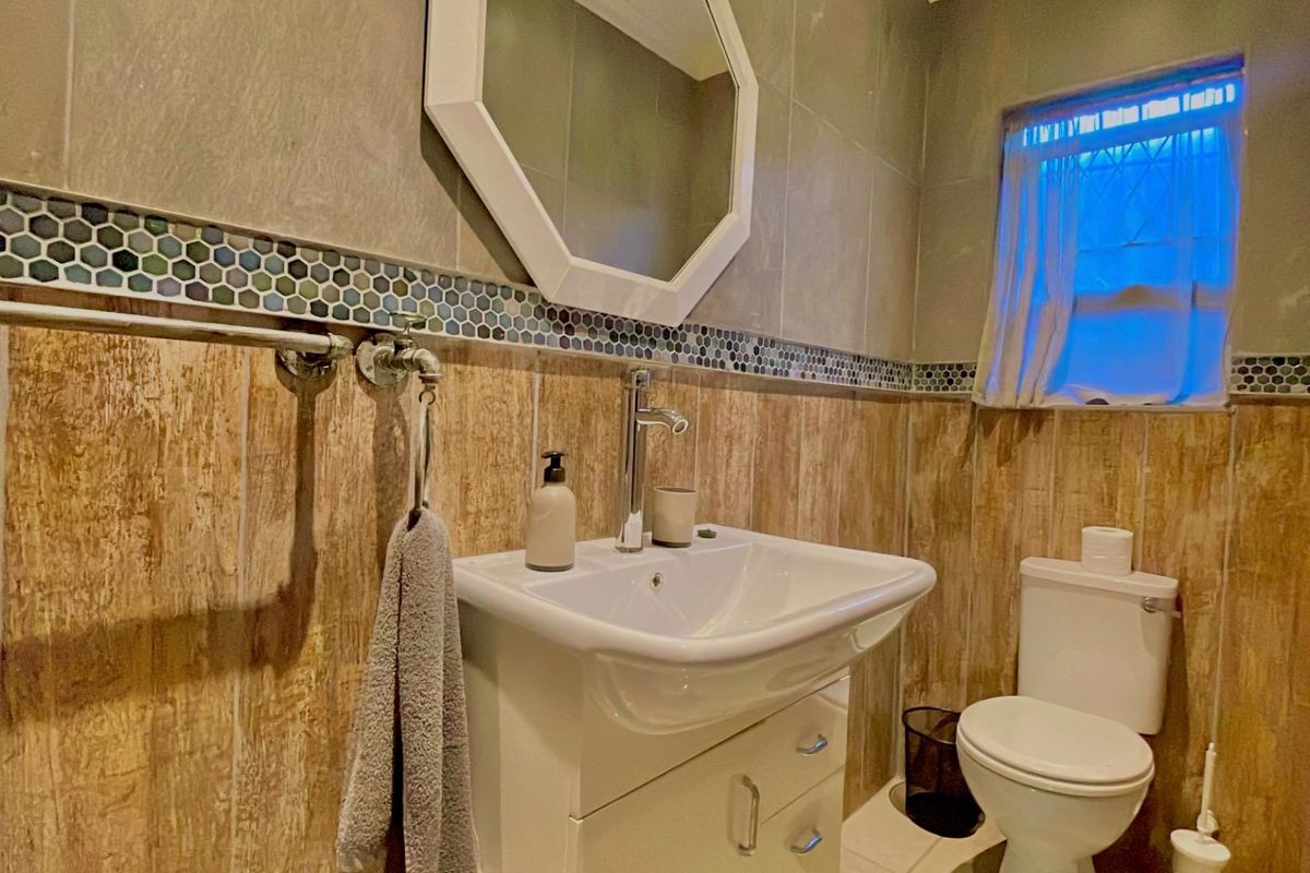 A well-maintained bathroom featuring a modern vanity with integrated basin, tiled walls with decorative mosaic accents, and a standard toilet.