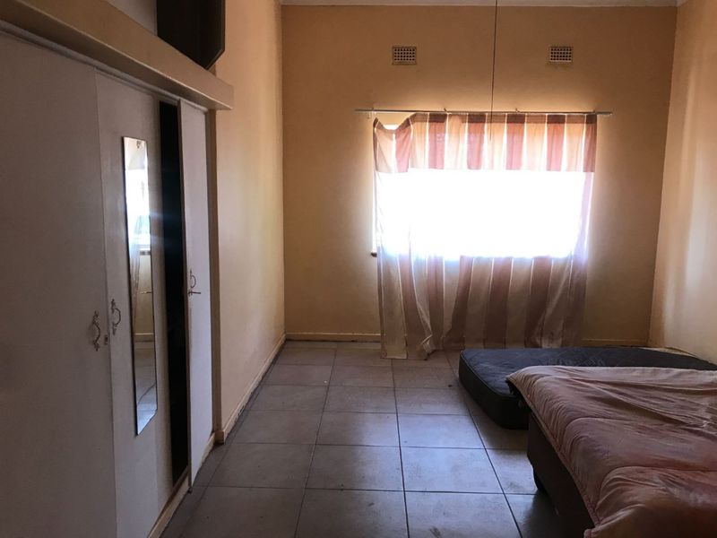 A bedroom featuring built-in cupboards and tiled flooring, requiring cosmetic updates to improve its overall appeal and condition.