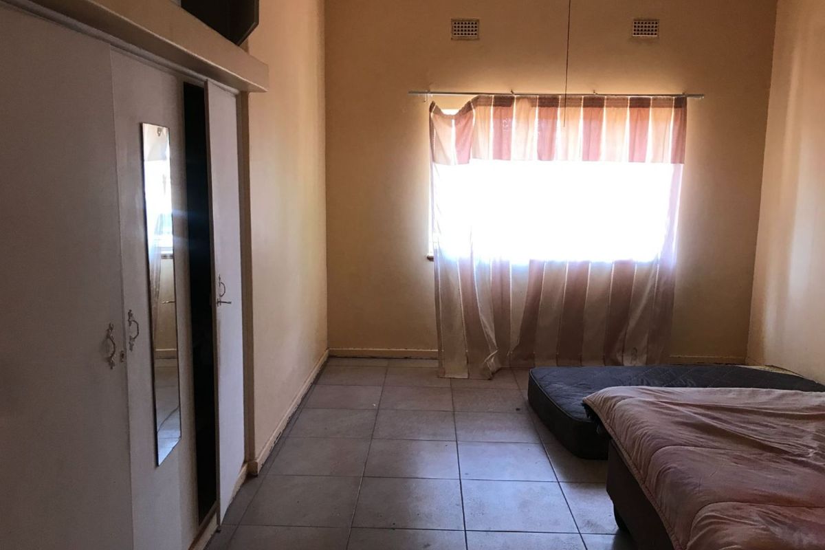 A bedroom featuring built-in cupboards and tiled flooring, requiring cosmetic updates to improve its overall appeal and condition.