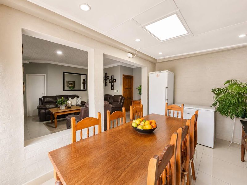 Open plan dining area featuring tiled flooring, recessed downlights, and a skylight, with an archway leading into the adjacent living room.