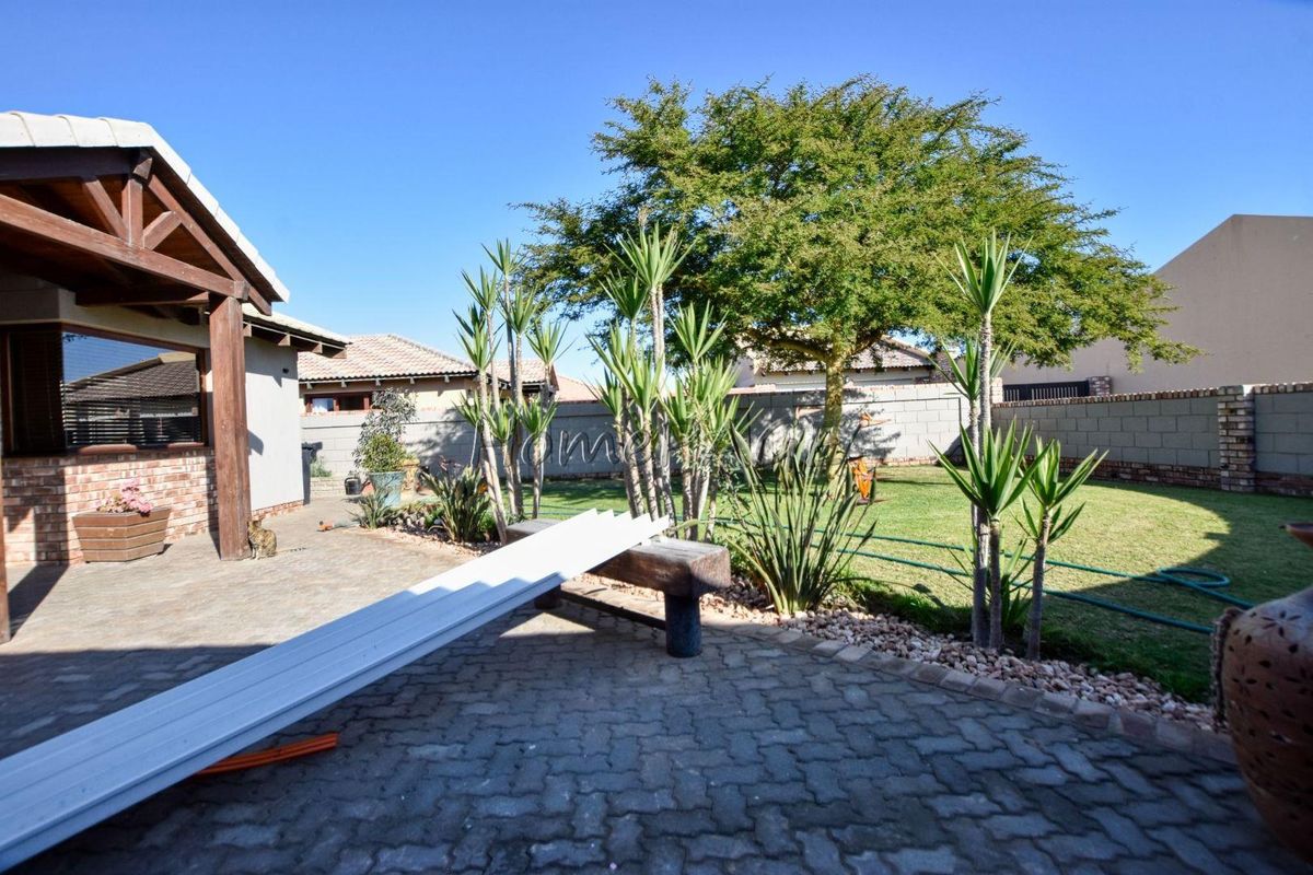 A rear garden featuring a paved patio area, established lawn, and perimeter boundary wall, providing a private outdoor space.