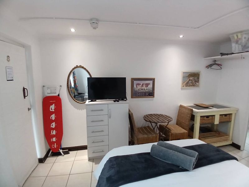 A compact bedroom featuring tiled flooring, recessed lighting, and surface-mounted electrical conduit, providing a functional living space.