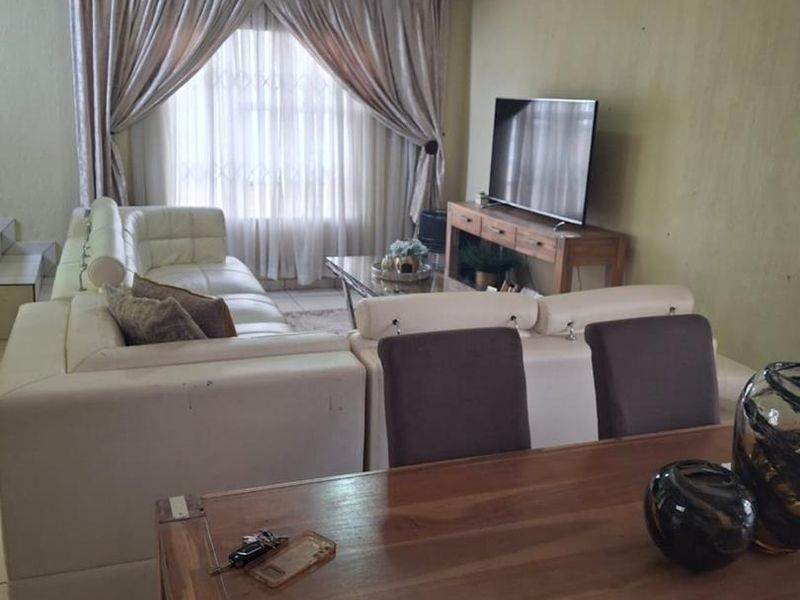 Open-plan living and dining area featuring tiled flooring and large window treatments, offering a functional space for relaxation and family meals.