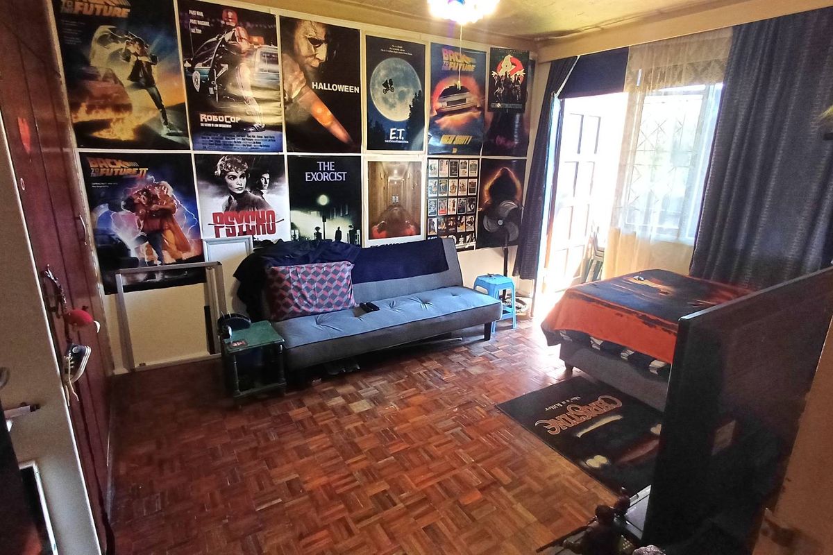 A living room featuring classic parquet flooring and direct access to an outdoor area through a security gate.