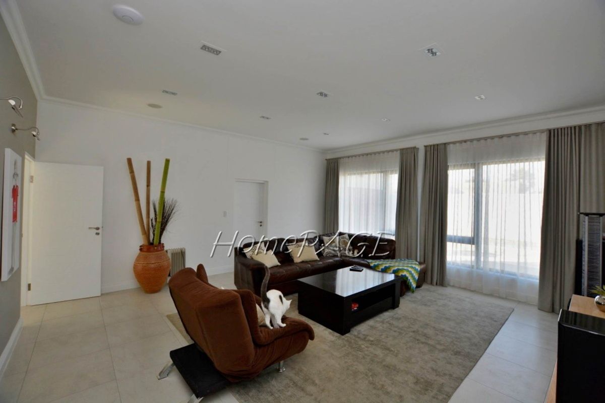 Spacious living room featuring large windows with floor-to-ceiling curtains, recessed ceiling lighting, and neutral tiled flooring.
