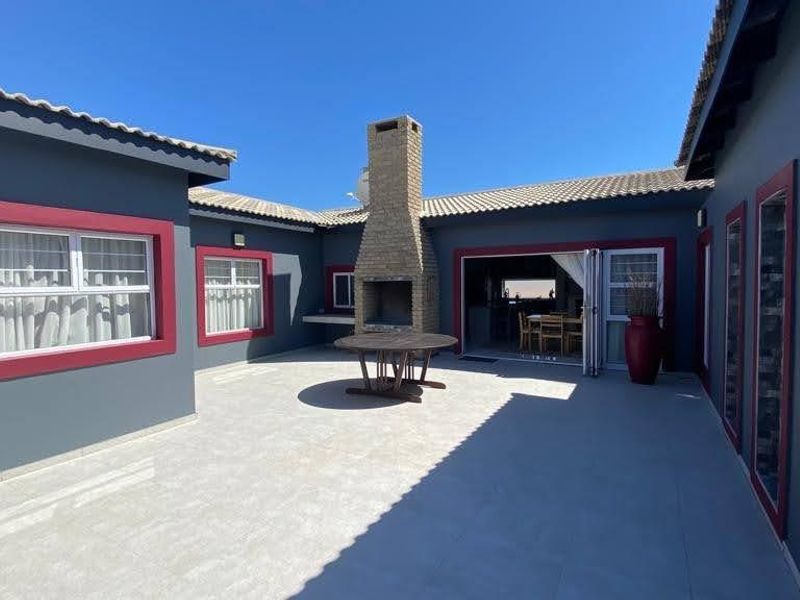 Spacious outdoor patio area featuring a built-in brick fireplace, tiled flooring, and bi-fold doors providing seamless access to the interior living space.