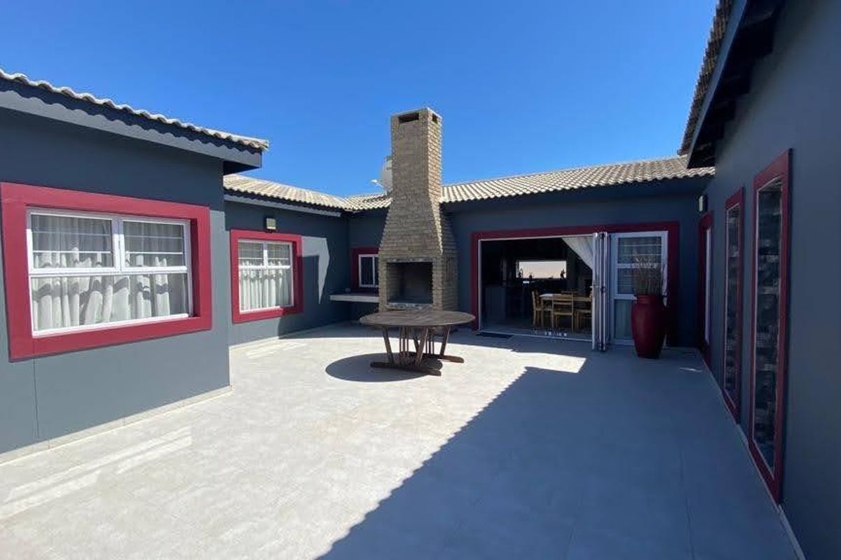 Spacious outdoor patio area featuring a built-in brick fireplace, tiled flooring, and bi-fold doors providing seamless access to the interior living space.
