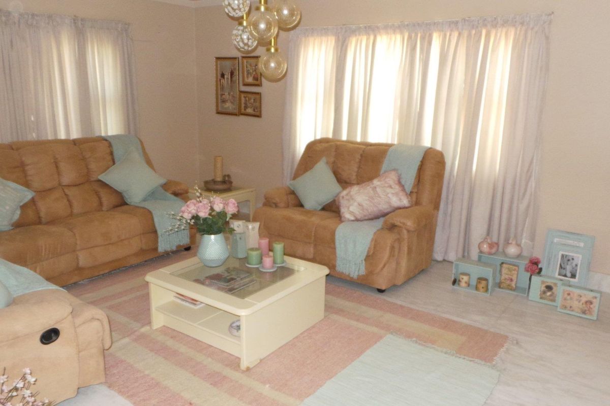 A comfortable living room featuring tiled flooring, neutral wall tones, and large windows with curtains, providing a bright and inviting space.