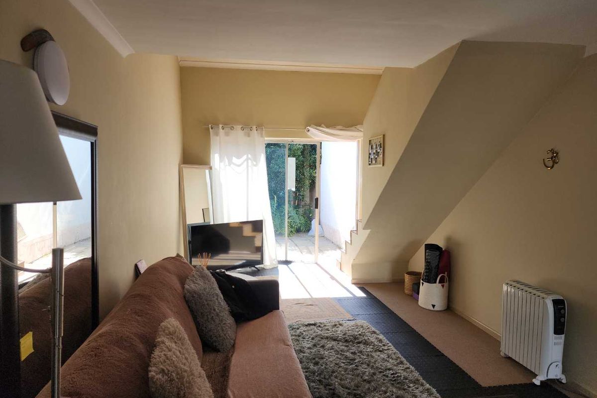 A living room area featuring a staircase and a sliding glass door providing access to the outdoor space.