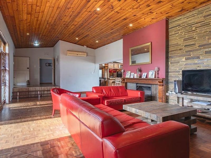 Spacious living room featuring a timber-clad ceiling, parquet flooring, and a prominent stone feature wall with an integrated fireplace.