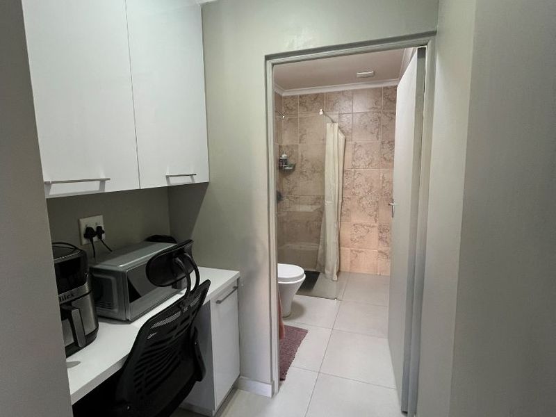 A functional utility space featuring built-in cabinetry and tiled flooring, providing direct access to an adjacent bathroom with a shower.