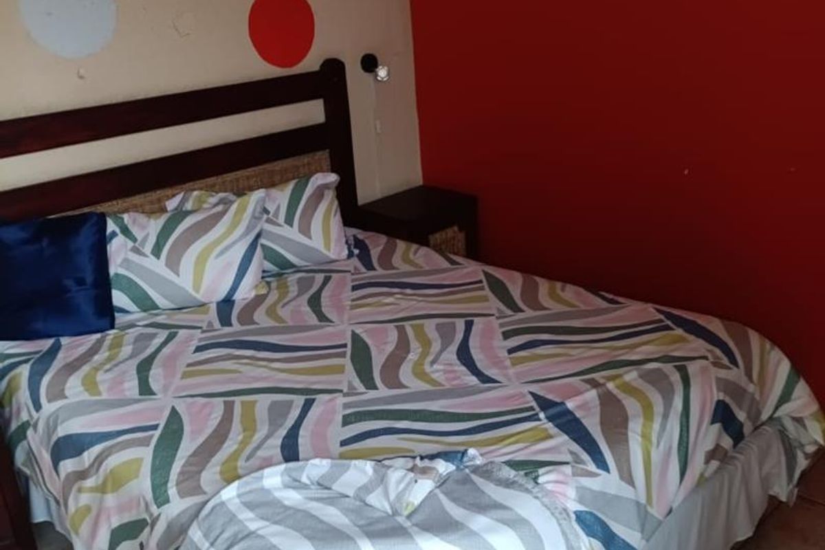 A bedroom featuring tiled flooring and a bold accent wall with decorative circular patterns.