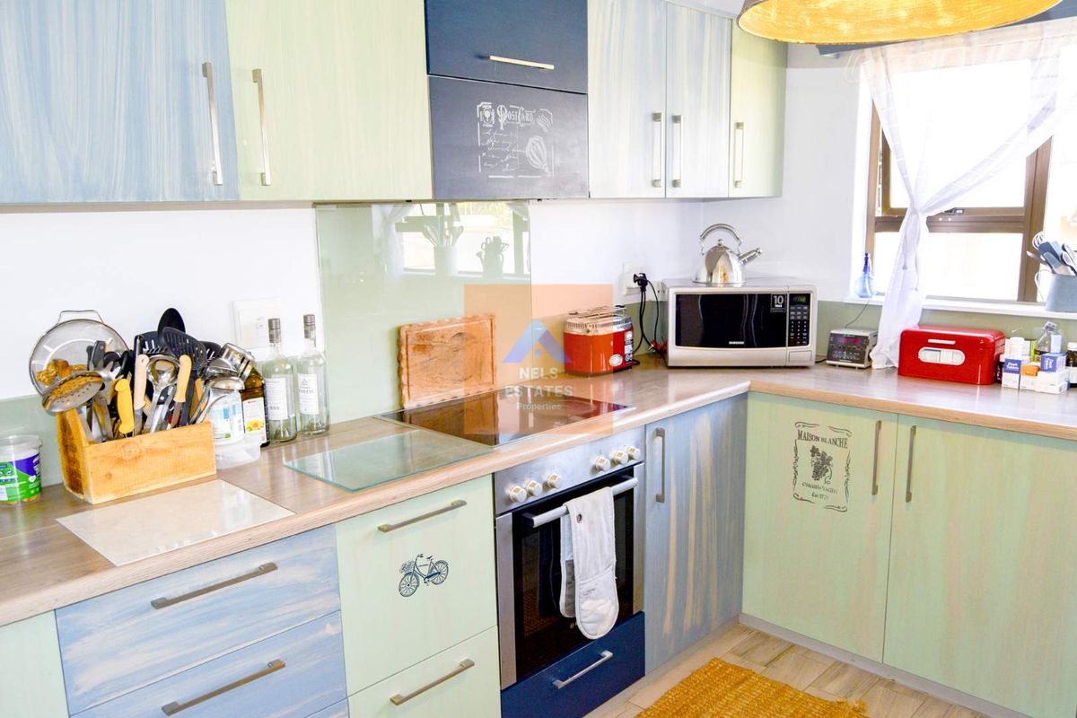 A functional kitchen featuring light-toned cabinetry, a built-in oven, a glass cooktop, and a glass splashback, providing a practical workspace.