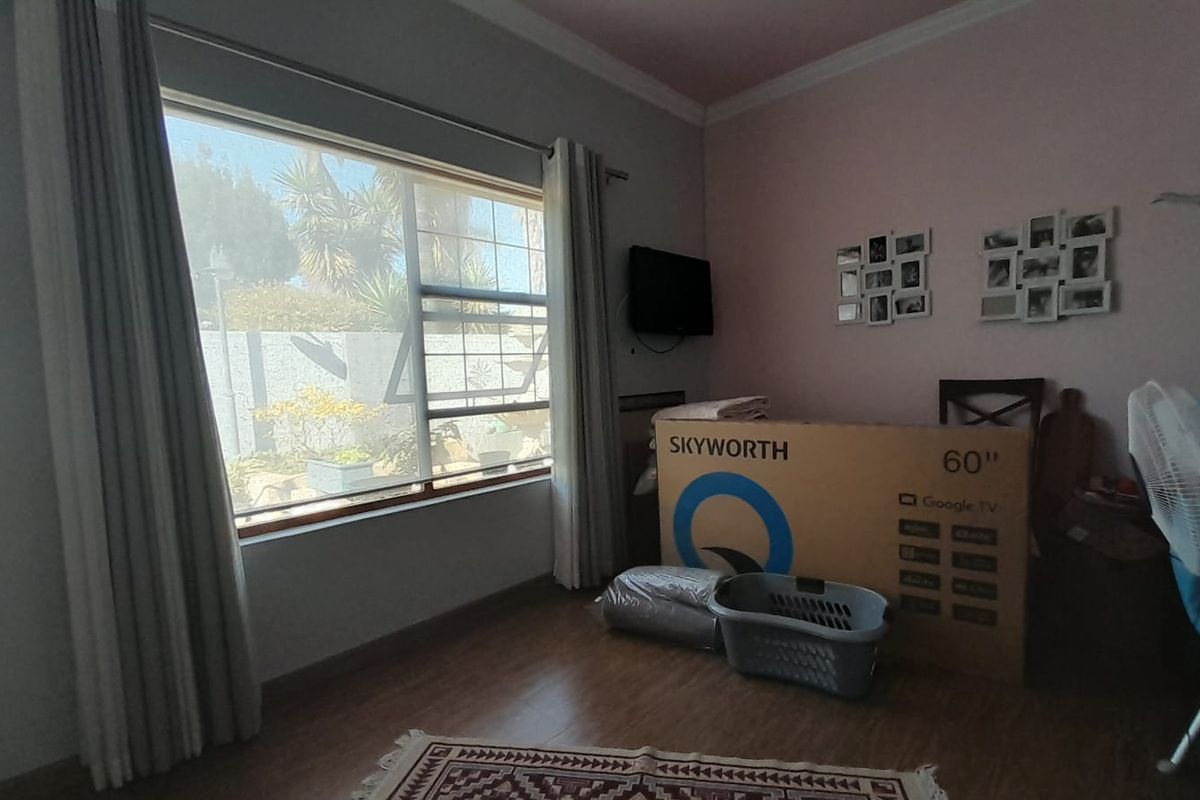 A bedroom featuring laminate flooring, a large window providing natural light, and decorative cove cornicing.