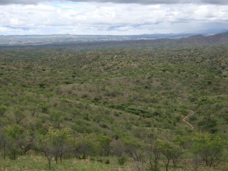 A wide-angle view of the expansive natural landscape, featuring rolling hills and native vegetation under a cloudy sky.