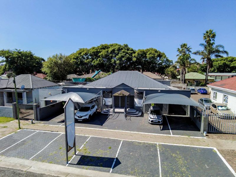 Aerial view of a commercial office property featuring a paved parking area, shade-net carports, and a well-maintained building facade.