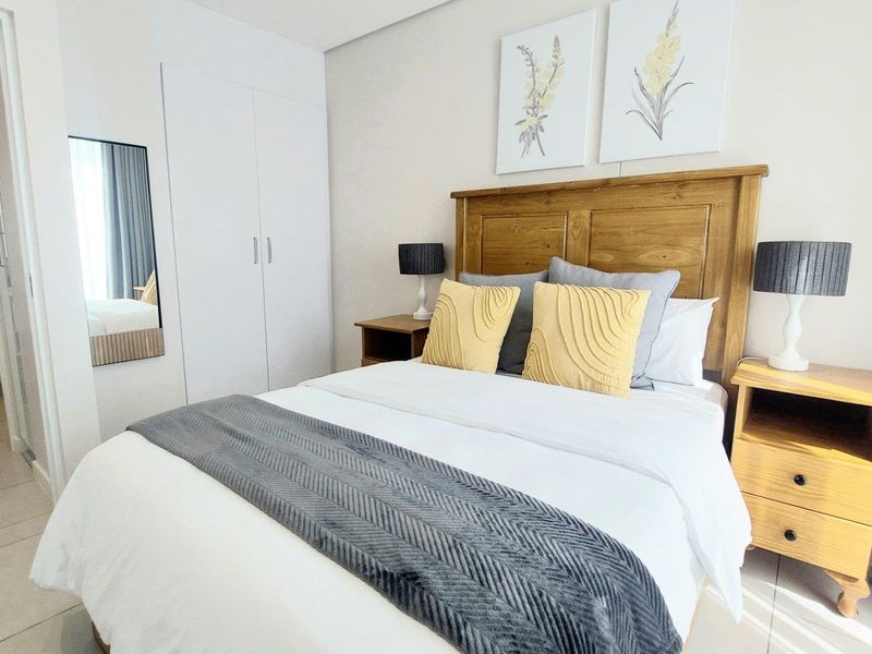 A well-maintained bedroom featuring built-in cupboards, neutral tiled flooring, and direct access to an en-suite bathroom.