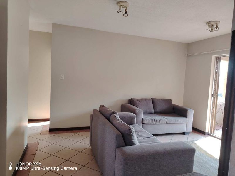 A living room area featuring tiled flooring and access to an outdoor space through a sliding glass door.