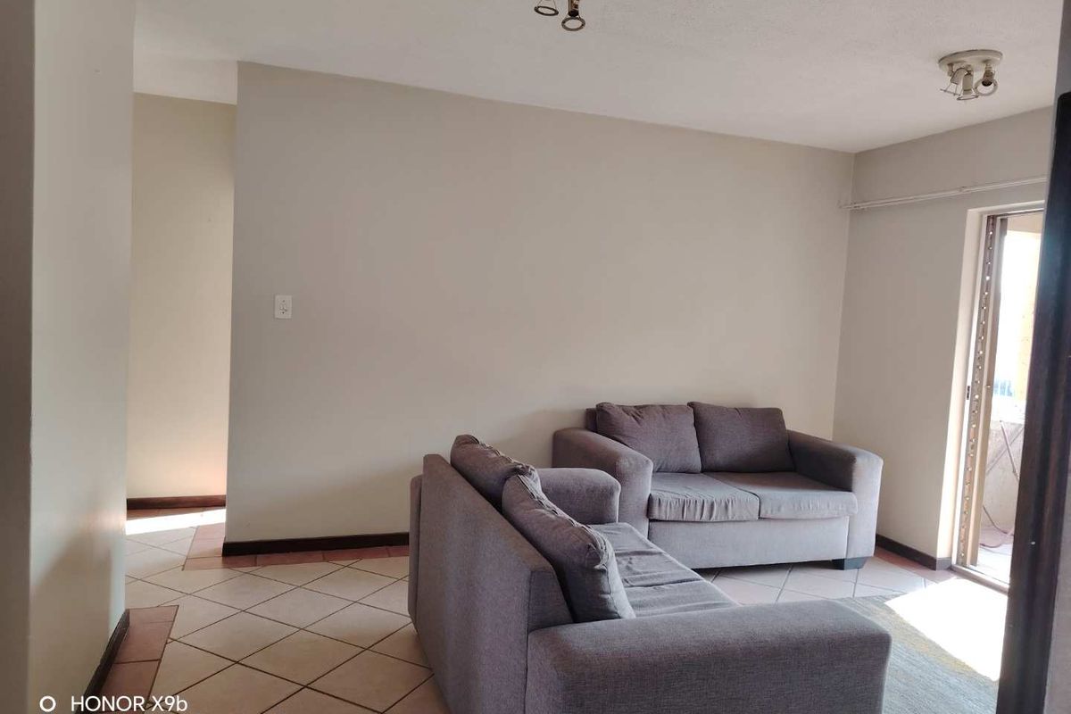 A living room area featuring tiled flooring and access to an outdoor space through a sliding glass door.