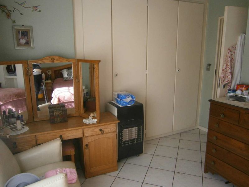 A bedroom featuring built-in cupboards and tiled flooring, offering a functional space with potential for modernization.