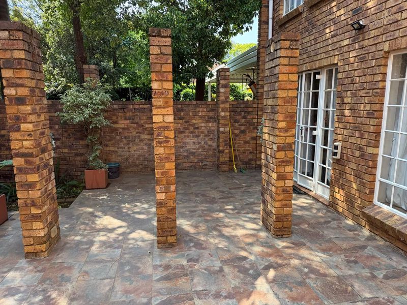 A private outdoor patio area featuring face brick columns, tiled flooring, and direct access to the interior through french doors.