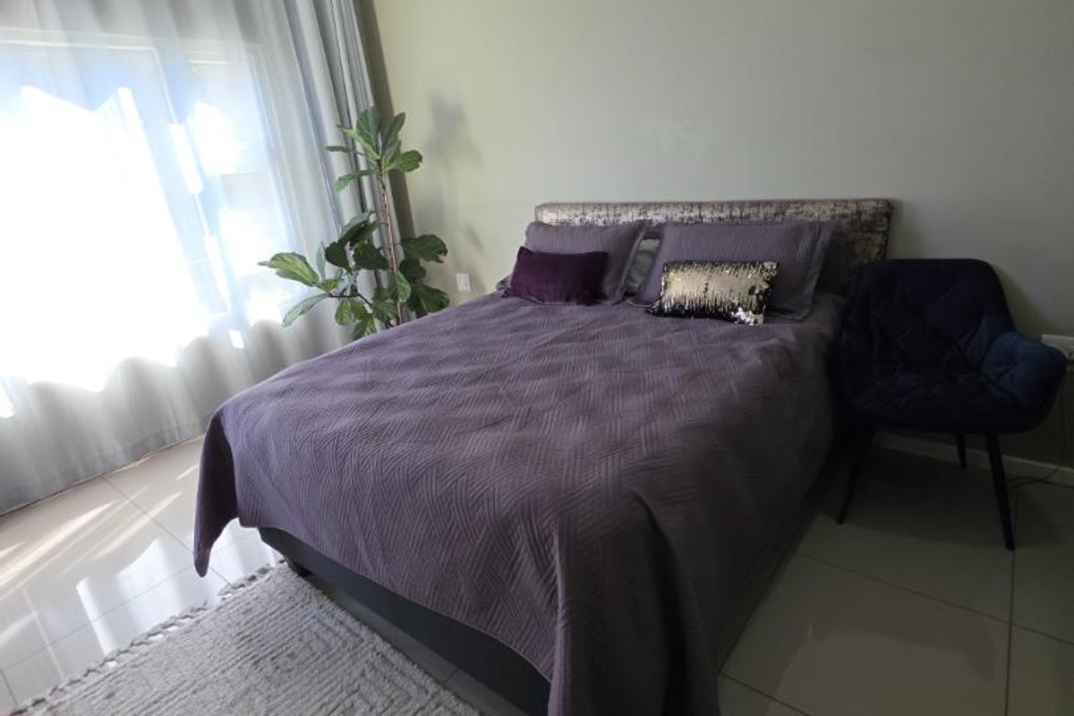 A well-maintained bedroom featuring neutral wall tones, large format floor tiles, and recessed ceiling lighting, providing a clean and comfortable living space.