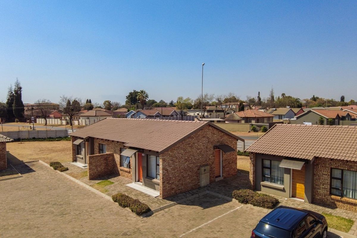 Aerial view of a residential townhouse complex featuring face-brick exteriors, tiled roofing, and paved driveway areas.