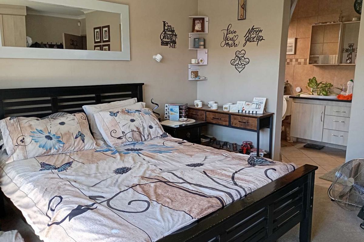 A bedroom featuring an open-plan layout with an attached en-suite bathroom, neutral wall tones, and tiled flooring in the bathroom area.
