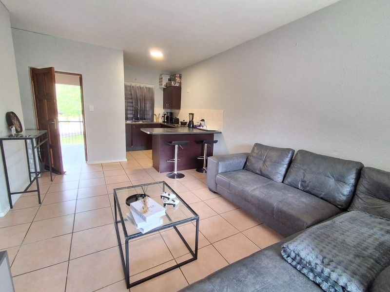 Open plan living area featuring a kitchen with dark cabinetry and tiled flooring, leading directly to an outdoor entrance.