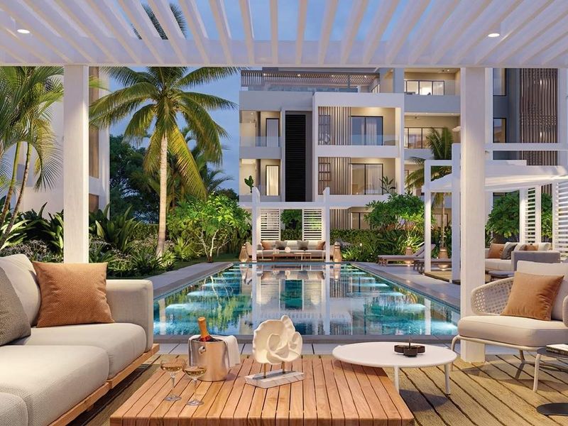 A beautifully landscaped pool area featuring a modern swimming pool, timber decking, and a pergola, set within a contemporary apartment complex.