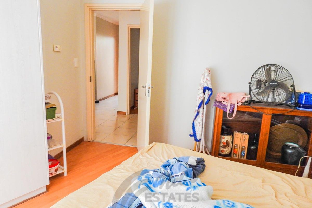 A bedroom featuring laminate flooring and built-in cupboard space, with an open doorway leading to an adjacent hallway.