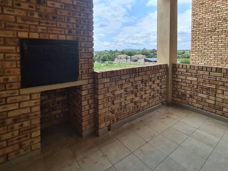 Covered balcony featuring a built-in brick braai, tiled flooring, and open views of the surrounding area.