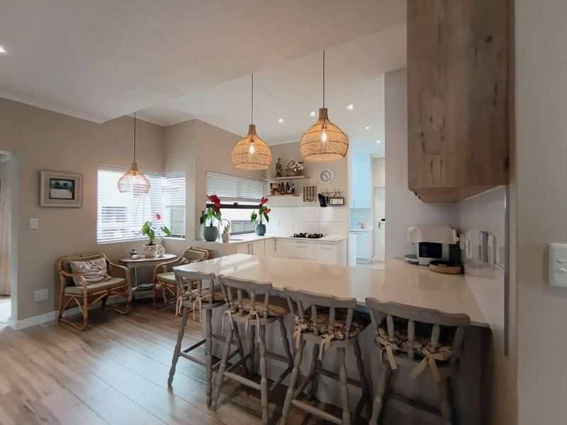Modern open-plan kitchen featuring a central island with quartz countertops, sleek cabinetry, and integrated gas hob, seamlessly flowing into the dining area.