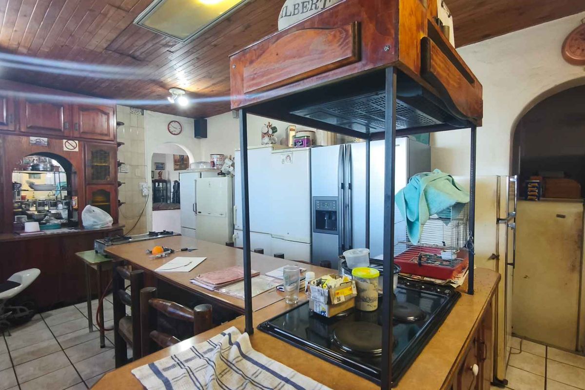 A spacious, rustic-style kitchen featuring extensive wooden cabinetry, a central island with a built-in hob, and a distinctive wooden ceiling.