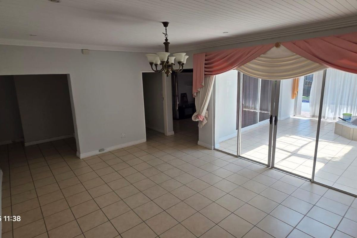 Spacious living area featuring tiled flooring, recessed lighting, and large sliding glass doors that provide access to an outdoor patio area.