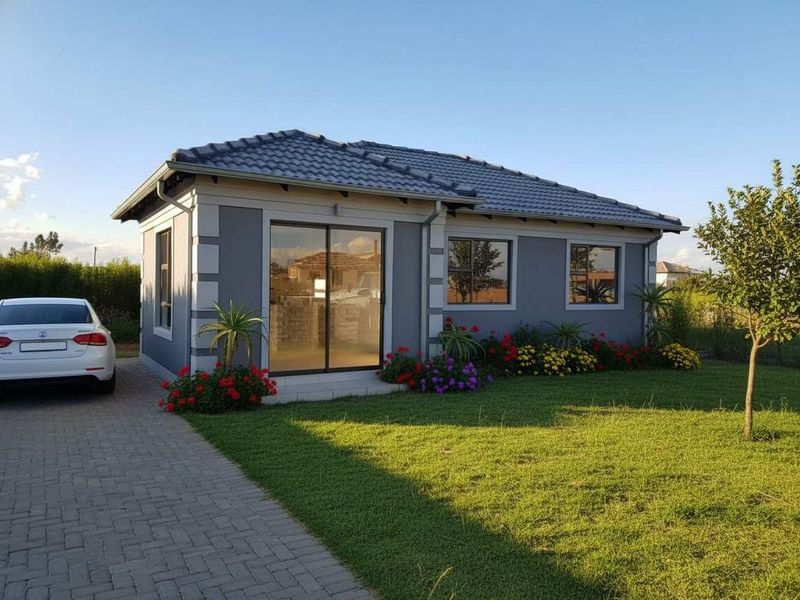 A well-maintained modern single-story home featuring a grey facade, tiled roof, and a paved driveway set within a neat garden.