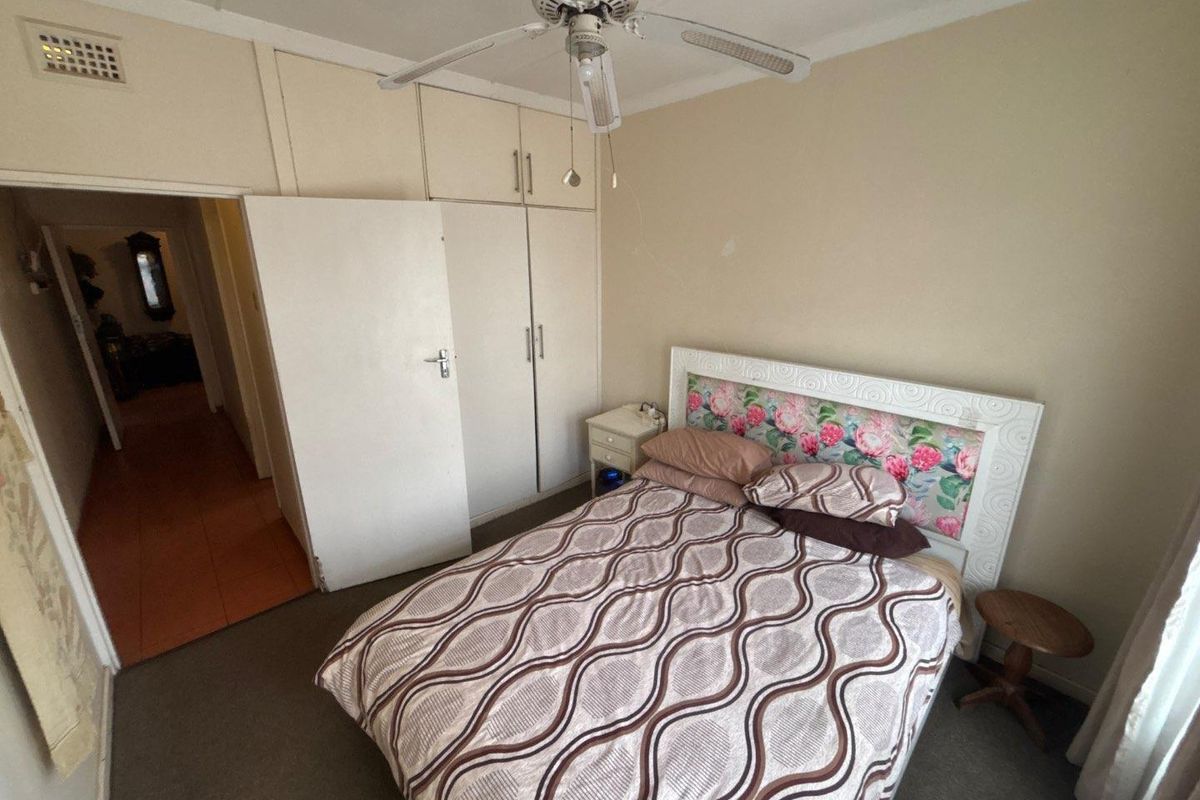 A bedroom featuring built-in cupboards, a ceiling fan, and carpeted flooring. The space requires cosmetic updates to improve its overall condition.